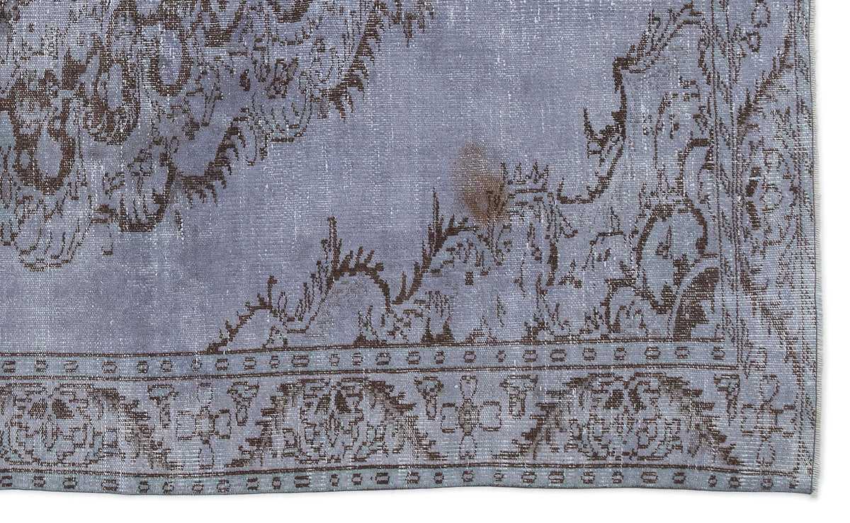 Periwinkle and dark brown distressed rug with a traditional floral medallion pattern and a geometric border.
