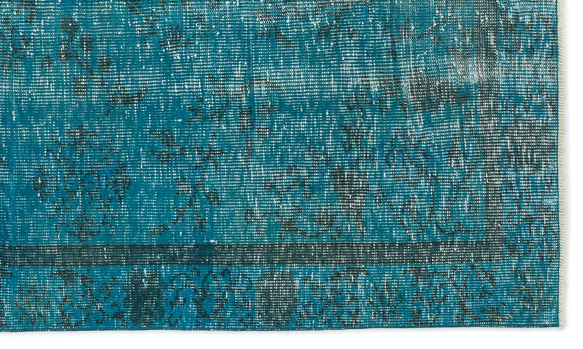 Teal and charcoal distressed rug with a faded traditional floral medallion pattern and a bordered edge.