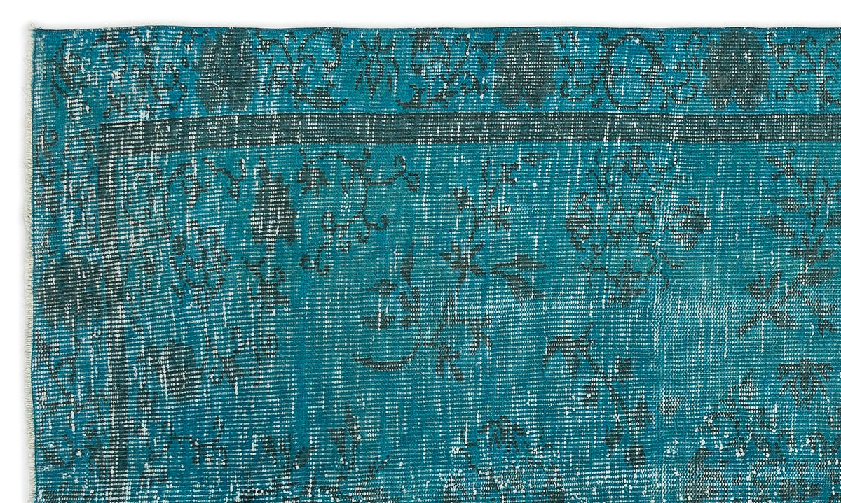 Teal and dark grey distressed rug with a traditional floral medallion pattern and a fringed edge.