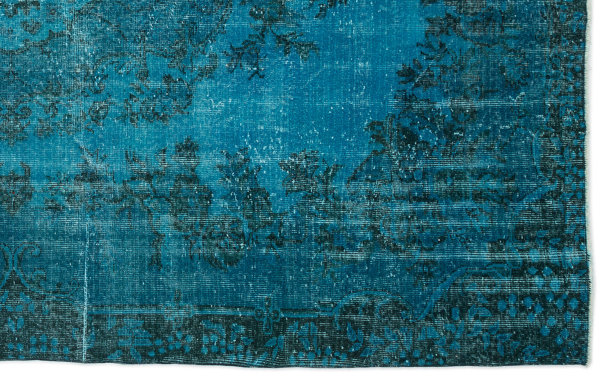 Teal and black distressed rug with a faded traditional floral pattern on a white background.