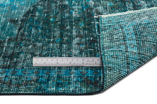 Load image 1 in gallery view. Teal and dark blue distressed rug with a faded traditional pattern, shown with a metal ruler for scale.