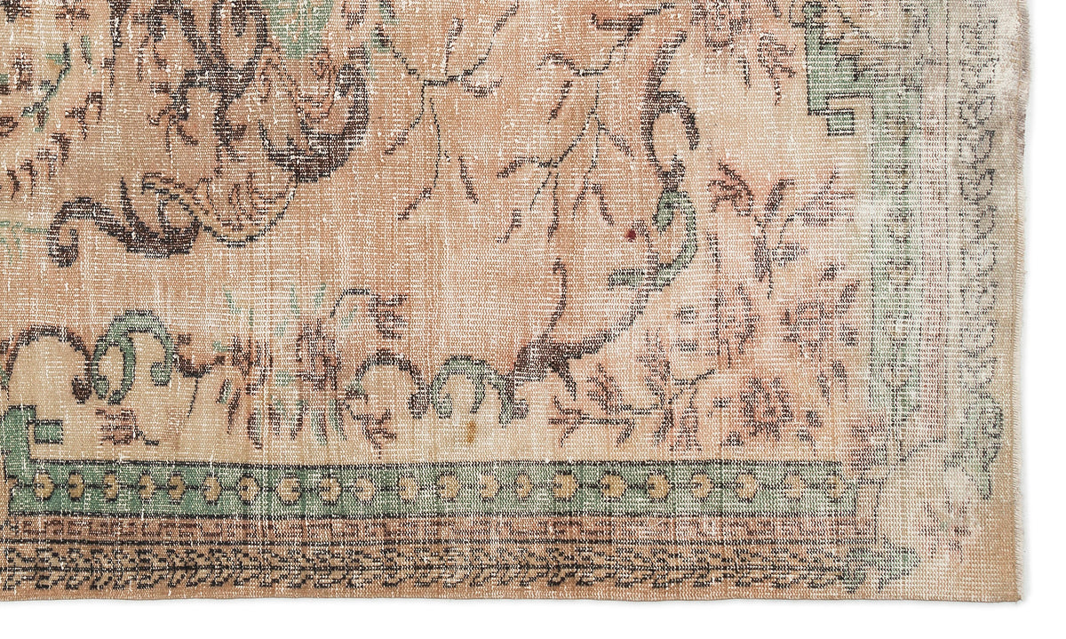 Distressed peach, sage green, and brown rug with a faded traditional floral pattern and geometric border.