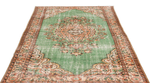 Load image 1 in gallery view. Distressed green rug with a central orange and cream floral medallion and ornate geometric border.