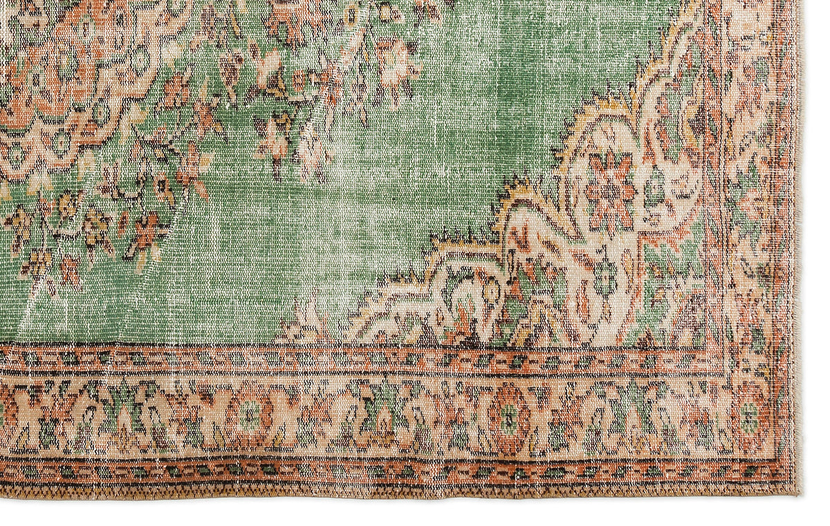 Distressed sage green and terracotta rug with a traditional floral medallion pattern and a detailed border.