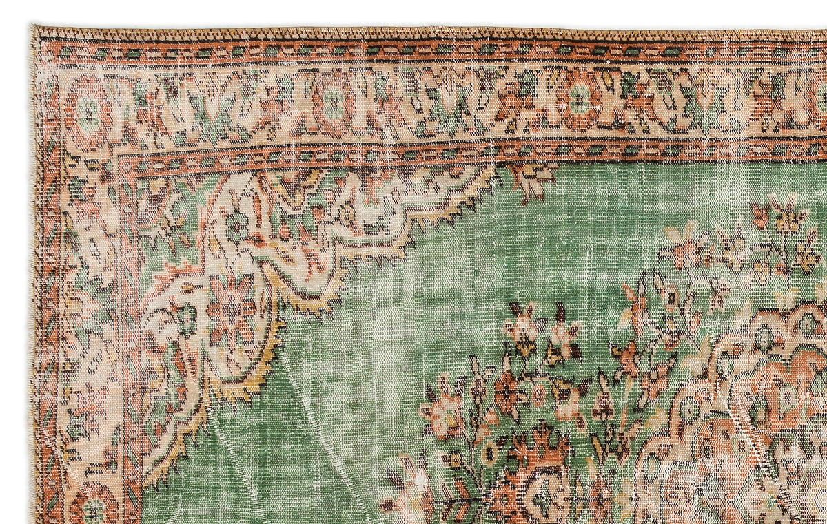 Green and terracotta vintage-style rug with a distressed floral medallion pattern and intricate geometric border.