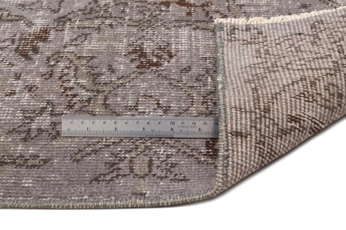 Load image 1 in gallery view. Grey and brown distressed floral rug with a folded corner and a metal ruler for scale on a white background.