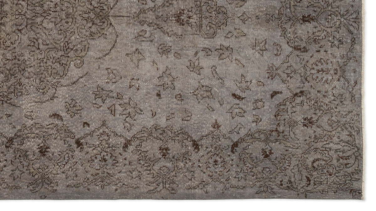 Grey and brown distressed rug with a traditional ornate floral medallion pattern and a fringed edge.