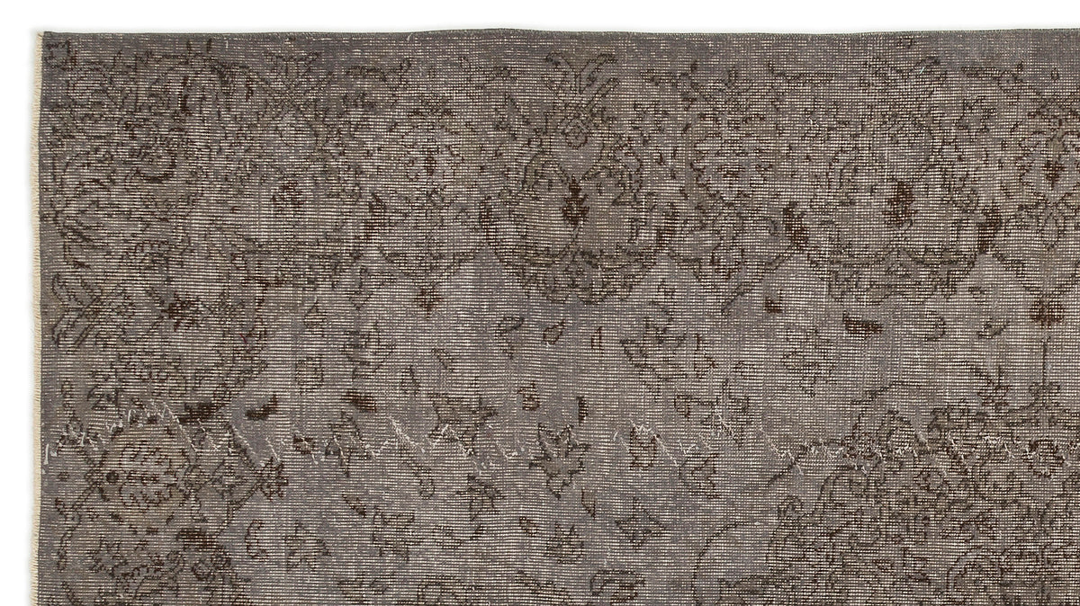 Charcoal grey distressed rug with a faded traditional floral medallion pattern.