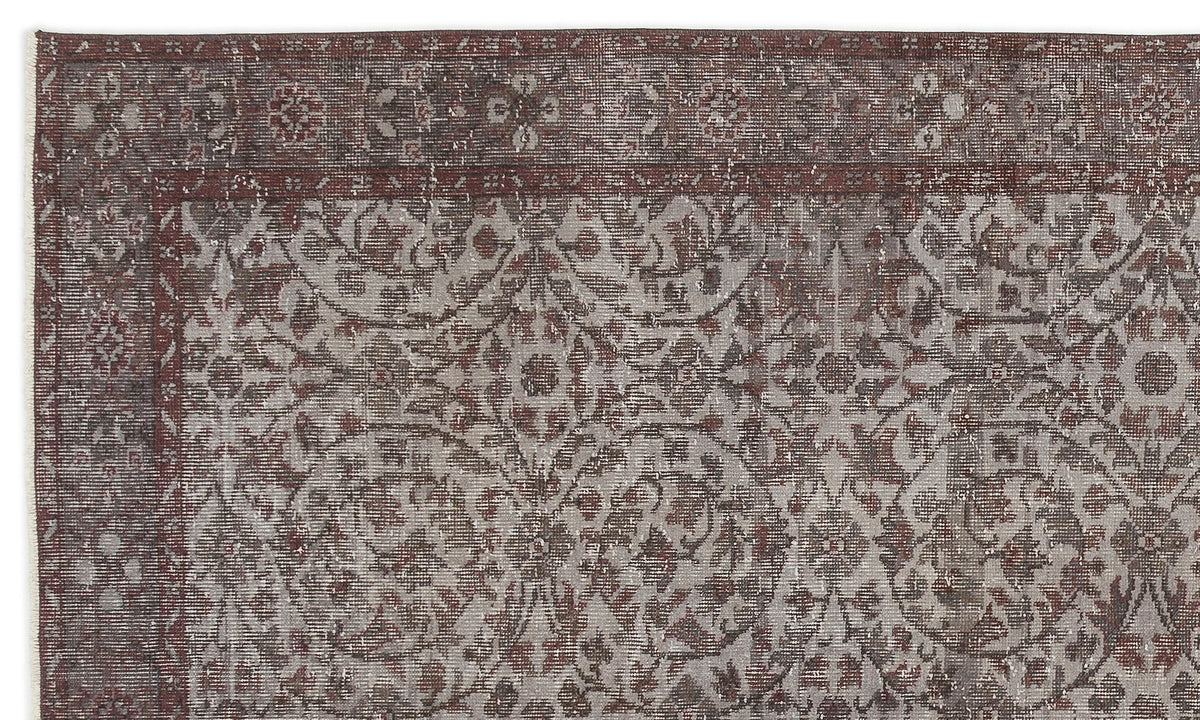 Distressed dark red and grey rug with a traditional floral medallion pattern and a wide decorative border.