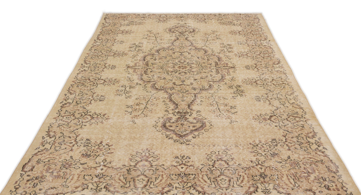 Beige and brown distressed area rug with a traditional central medallion and floral border pattern.