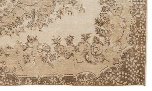 Load image 1 in gallery view. Beige and brown vintage-style rug with a distressed floral medallion pattern.