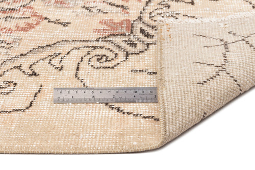 Load image 1 in gallery view. Beige and cream vintage-style rug with a faded floral pattern and a metal ruler for scale.