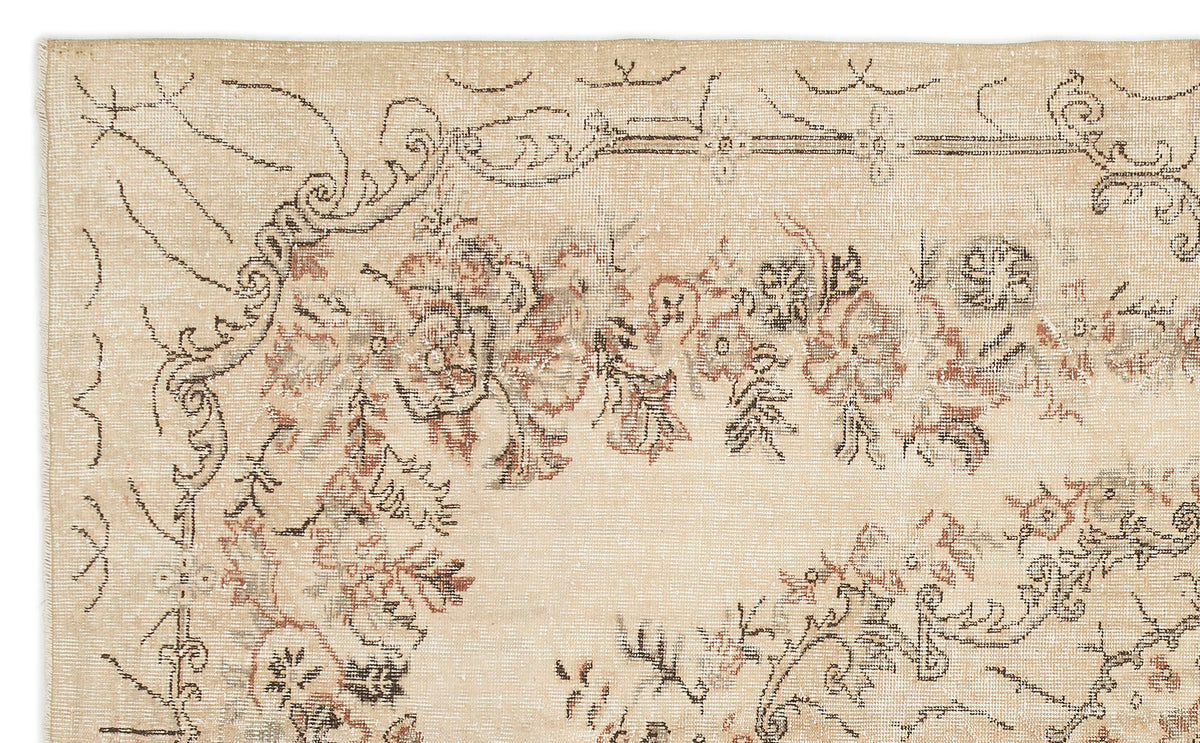 Beige vintage-style rug with a distressed floral medallion pattern in muted brown, charcoal, and faded red tones.