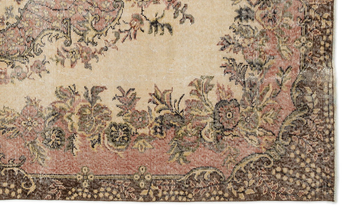 Beige, pink, and dark brown vintage-style rug with a distressed floral border and central medallion pattern.