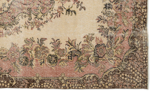 Load image 1 in gallery view. Beige, pink, and dark brown vintage-style rug with a distressed floral border and central medallion pattern.