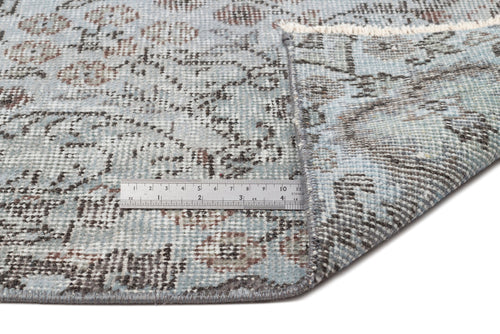 Load image 1 in gallery view. Light blue and grey distressed rug with a traditional floral pattern, shown with a metal ruler for scale.