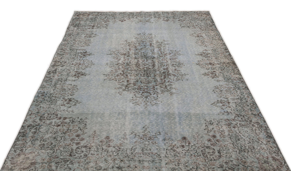Light blue and grey distressed rug with a central floral medallion and ornate border pattern on a white background.