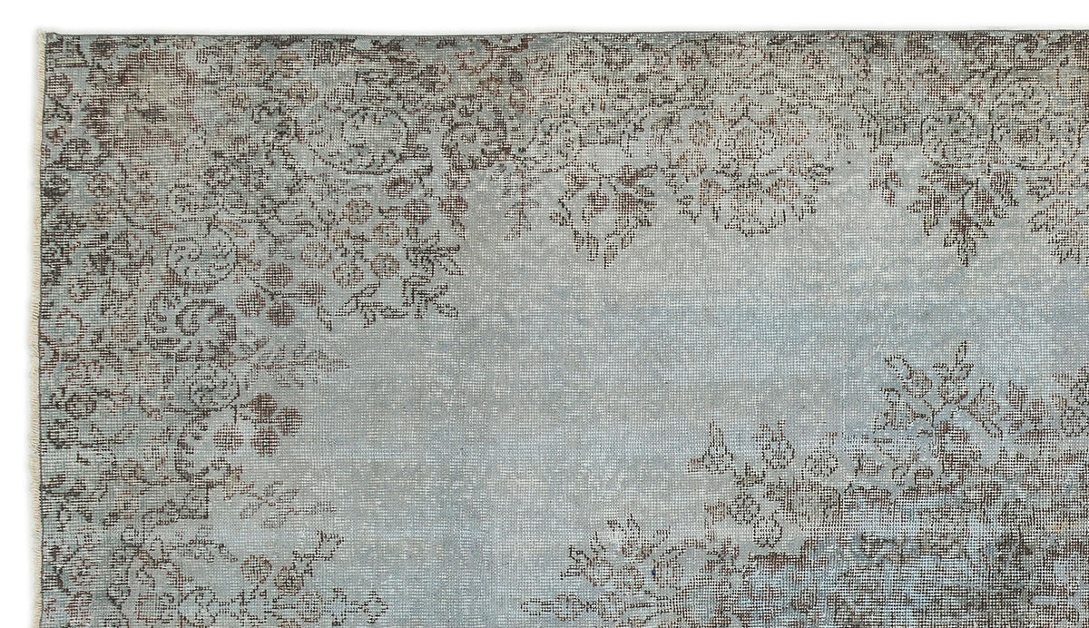 Light blue and grey distressed rug with a faded floral medallion pattern.