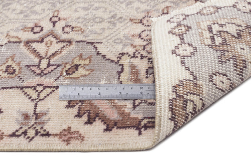 Load image 1 in gallery view. Beige and grey traditional floral rug with a corner folded back to show the weave, featuring a metal ruler for scale.