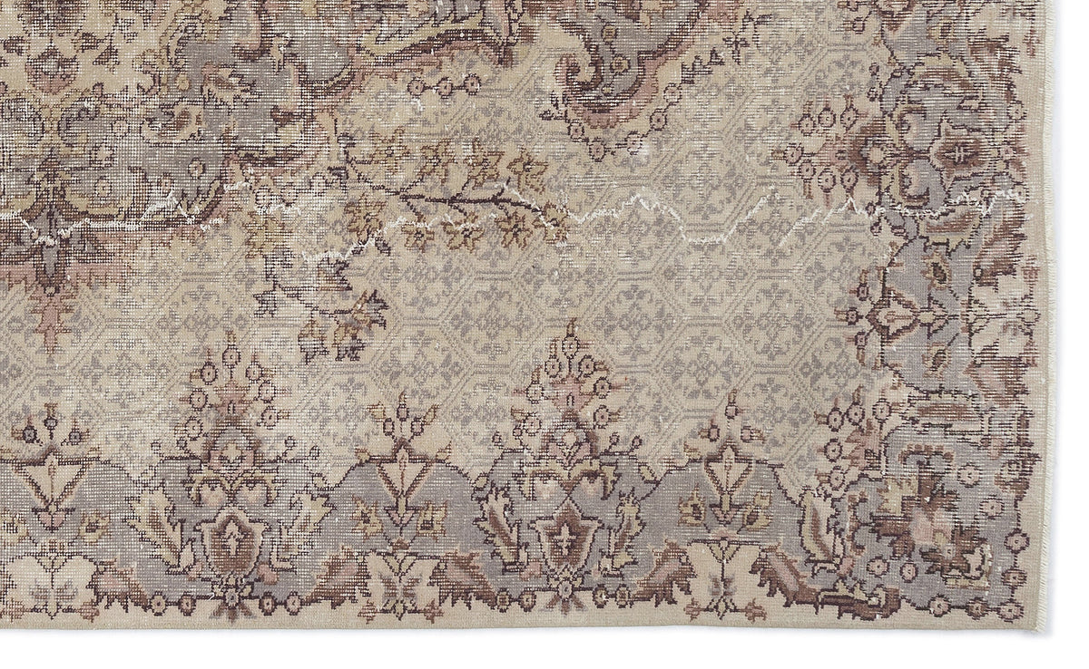 Beige and grey distressed rug with a traditional floral medallion pattern and a geometric lattice background.
