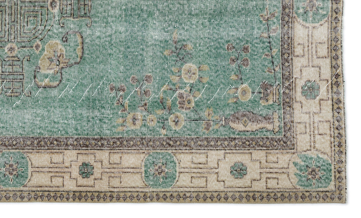 Teal and beige rug with a distressed floral center and a geometric border featuring circular motifs.