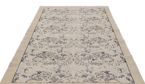 Load image 1 in gallery view. Beige area rug with a distressed floral pattern in muted blue and charcoal gray on a white background.