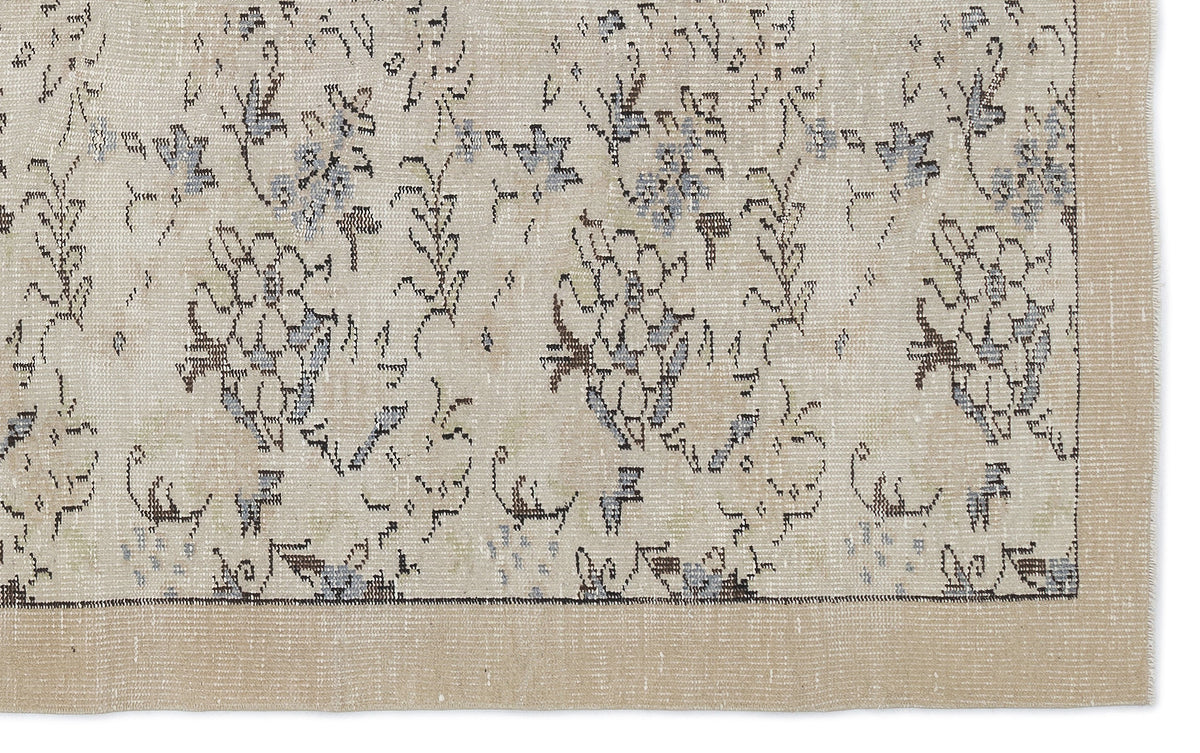 Beige rug with a distressed floral pattern in muted blue and charcoal, featuring a solid border.