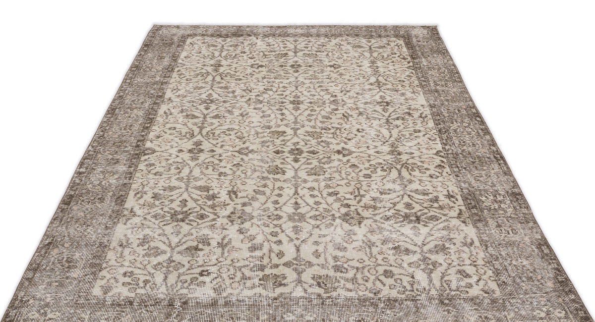 Taupe and cream distressed rug with a traditional floral medallion pattern and a wide decorative border.