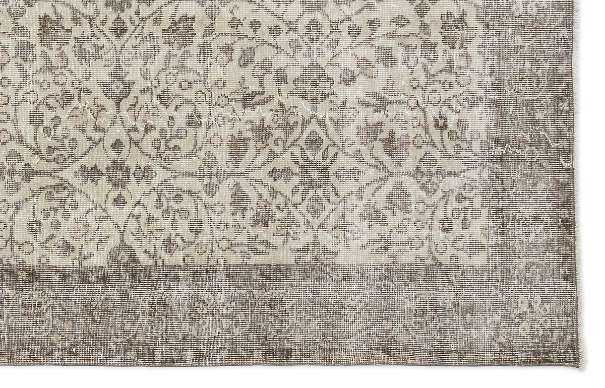 Beige and brown rug with a distressed traditional floral medallion pattern and a wide decorative border.