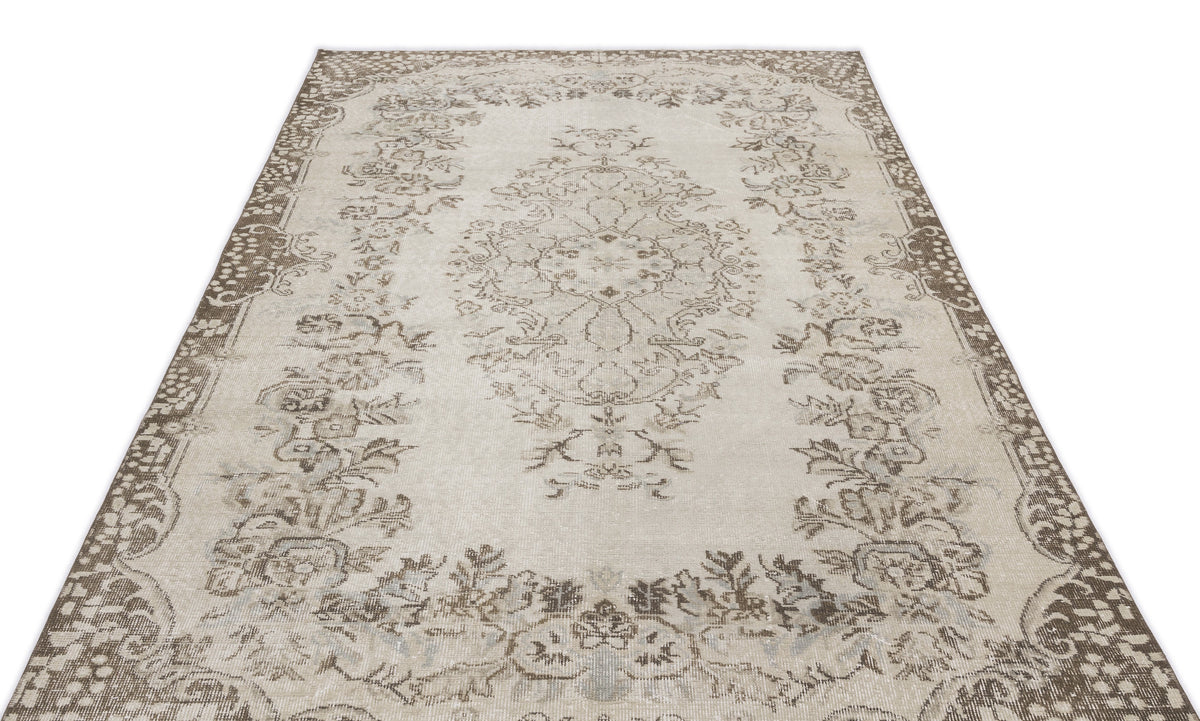 Beige and brown vintage-style rug with a central floral medallion and ornate border on a white background.