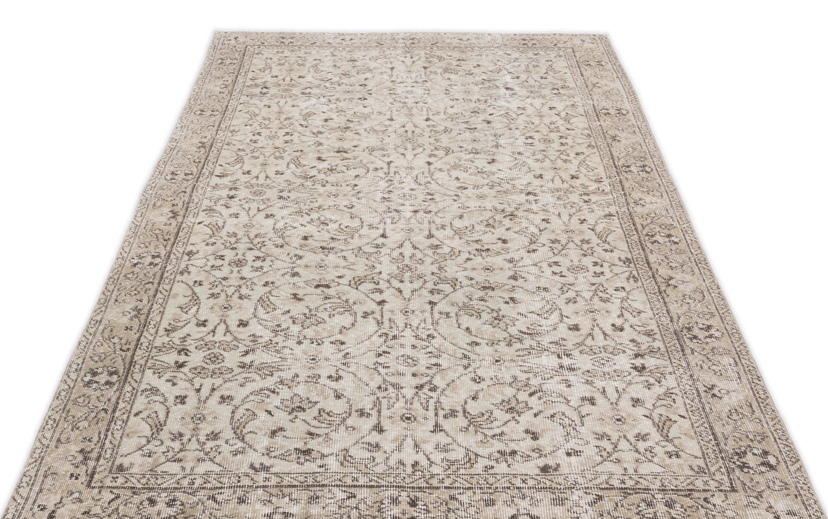 Beige and taupe vintage-style rug with a distressed floral medallion pattern and a detailed border on a white background.