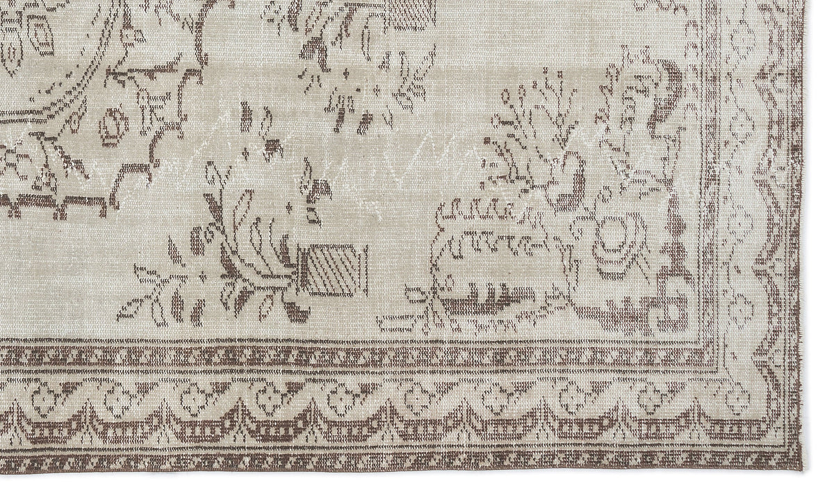 Beige and brown rug with a distressed traditional floral pattern and a geometric border.