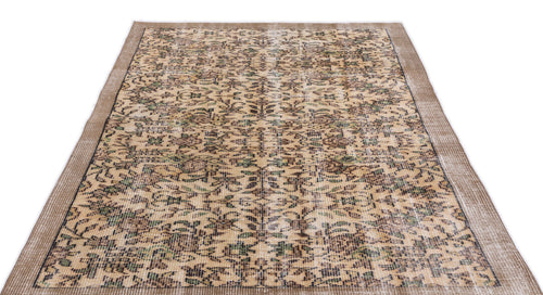 Load image 1 in gallery view. Tan and brown distressed vintage-style rug with a repeating floral medallion pattern and a textured border.