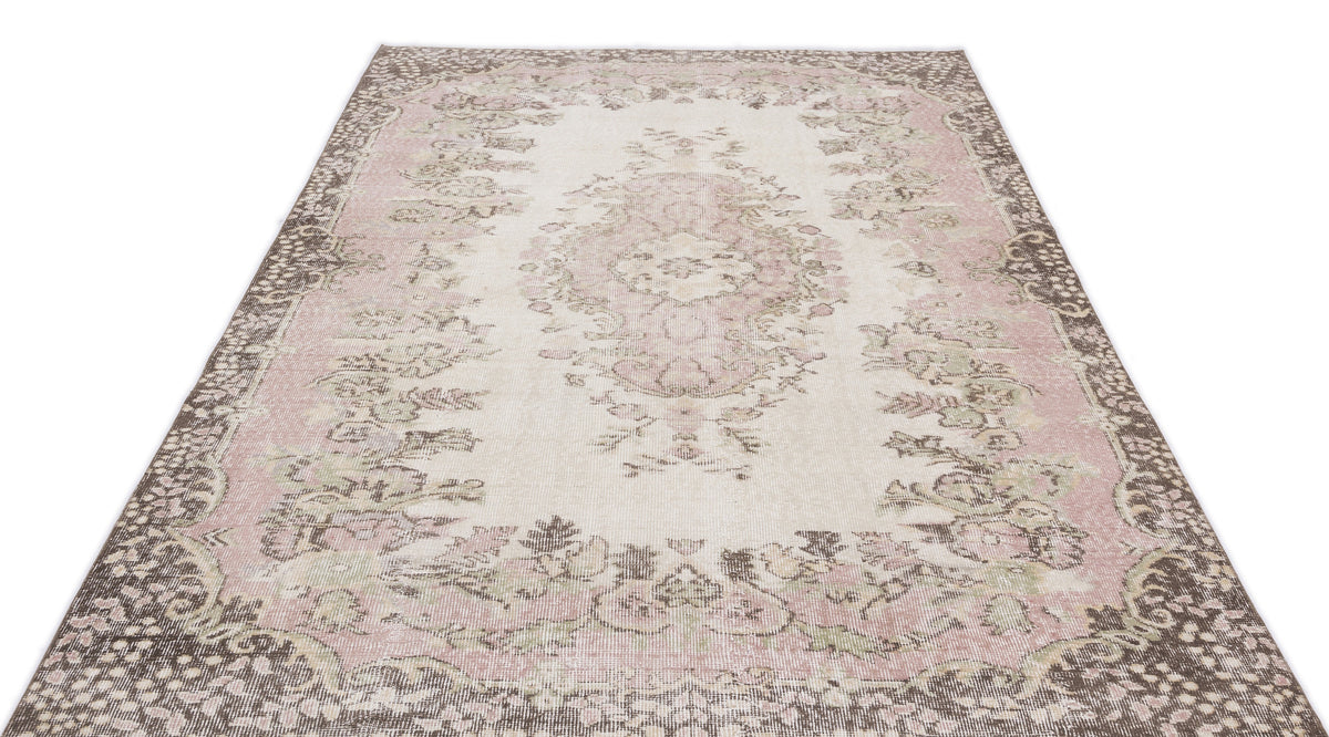 Cream, pink, and brown distressed rug with a traditional floral medallion pattern on a white background.