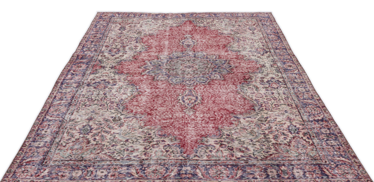 Distressed red and blue vintage-style rug with a central floral medallion and ornate border on a white background.