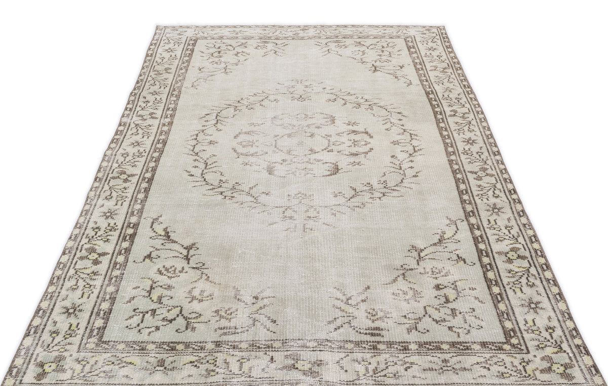 Beige and brown distressed area rug with a central floral medallion and a decorative botanical border.