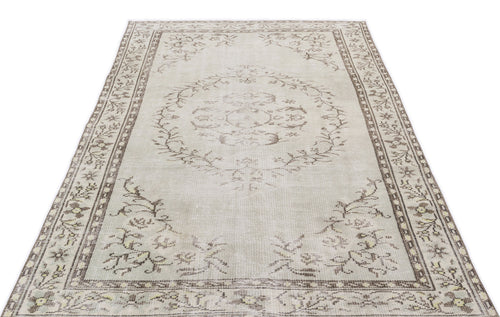 Load image 1 in gallery view. Beige and brown distressed area rug with a central floral medallion and a decorative botanical border.