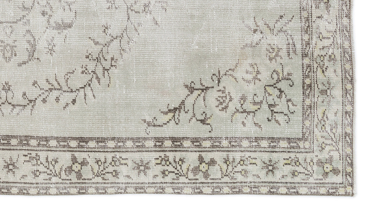 Light gray and taupe vintage-style rug with a distressed floral medallion pattern and a geometric border.