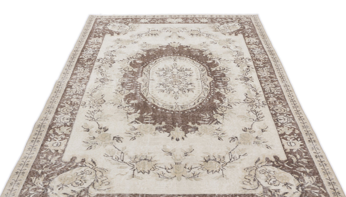 Cream and brown traditional rug with a central floral medallion and ornate border on a white background.