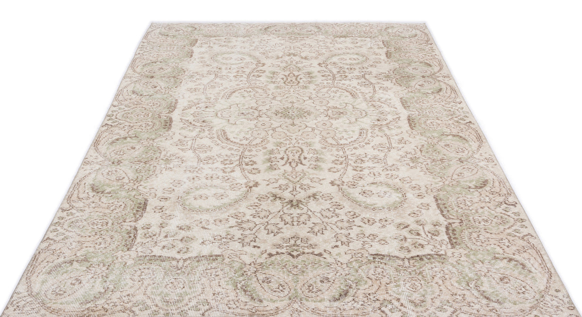 Beige and sage green distressed area rug with a traditional floral medallion pattern on a white background.