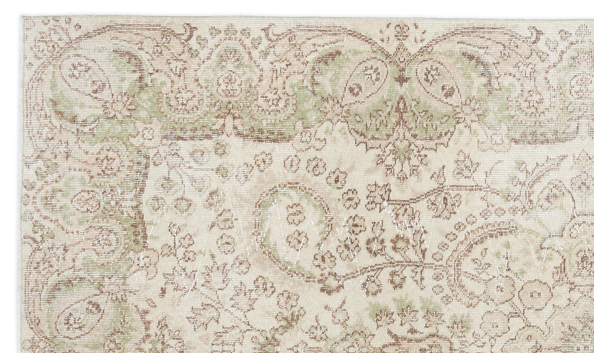 Beige rug with a distressed, faded floral paisley pattern in sage green and brown tones.