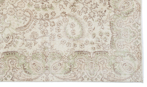 Load image 1 in gallery view. Cream rug with a distressed, faded floral medallion pattern in sage green and brown tones.