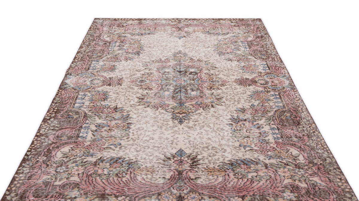 Distressed beige rug with a faded floral medallion pattern in muted pink, blue, and brown tones.