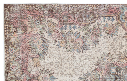 Load image 1 in gallery view. Distressed vintage-style rug with a brown, cream, pink, and blue floral medallion pattern.