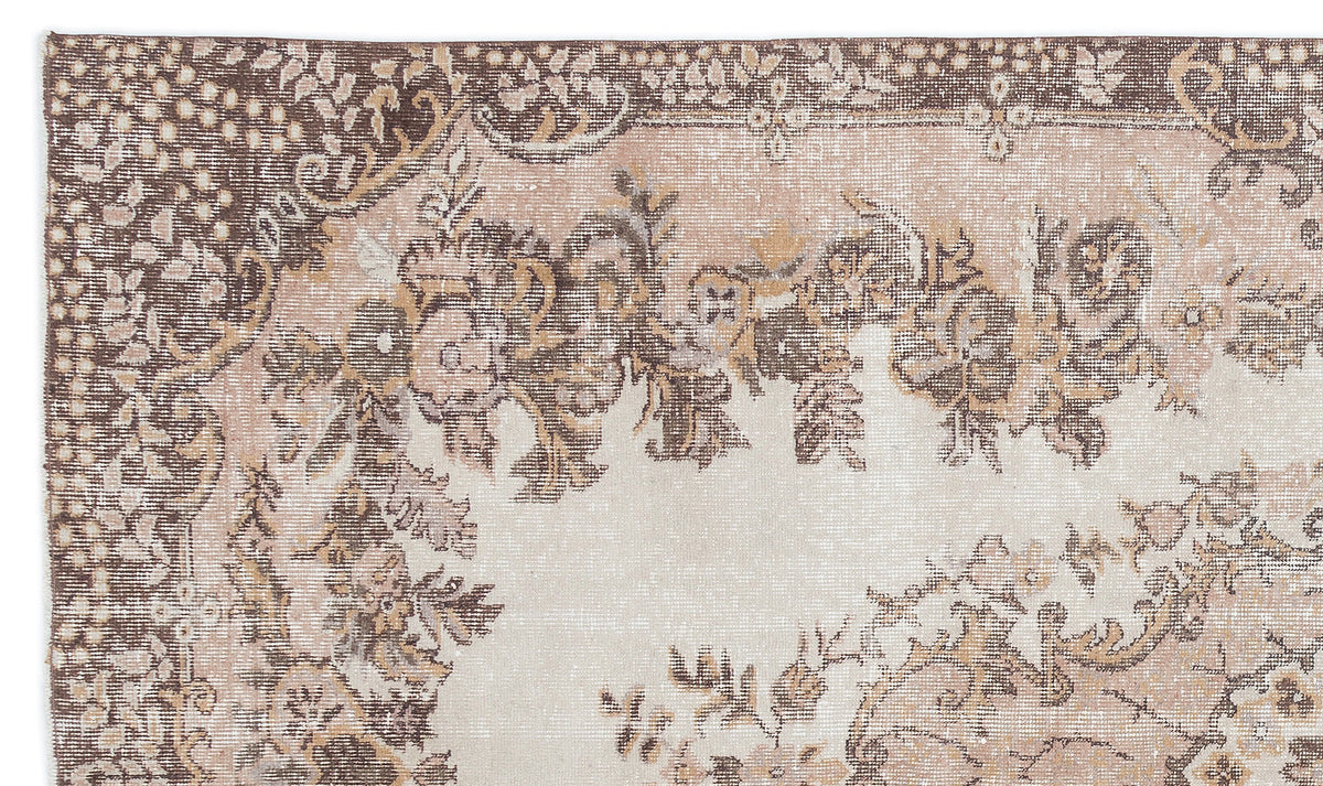 Distressed beige and brown rug with a traditional floral medallion pattern and ornate border.