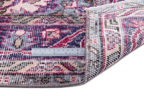 Load image 1 in gallery view. Distressed floral medallion rug in magenta, navy, and cream with a folded corner and a metal ruler for scale.