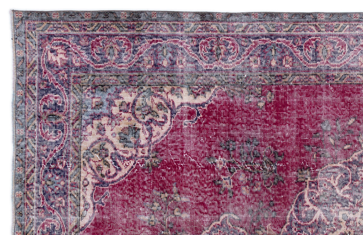 Distressed magenta and navy blue traditional rug with an ornate floral medallion border and faded vintage finish.