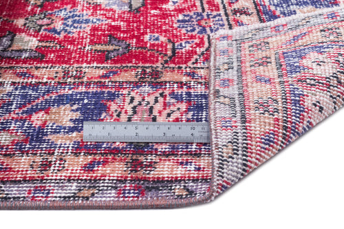 Load image 1 in gallery view. Distressed red, blue, and beige vintage-style rug with a folded corner and a metal ruler for scale.