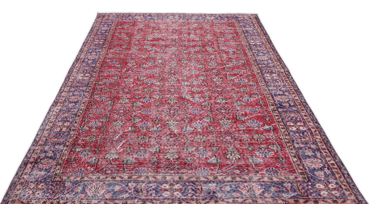 Red and blue traditional Persian-style rug with a distressed floral pattern and a wide decorative border.