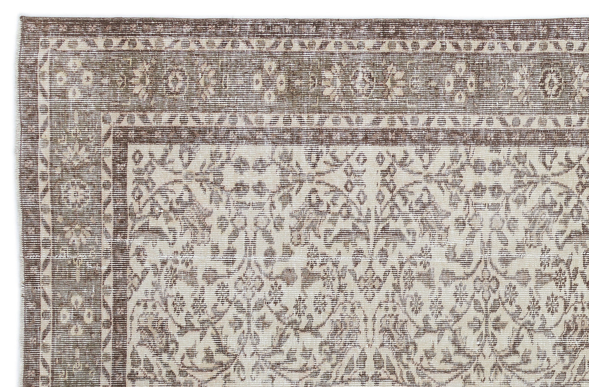 Brown and cream vintage-style rug with a distressed floral medallion pattern and a geometric border.